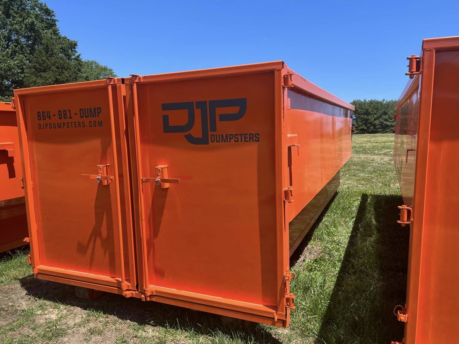 Close-up of the rear swing doors on an orange DJP dumpster, showing the latch hardware